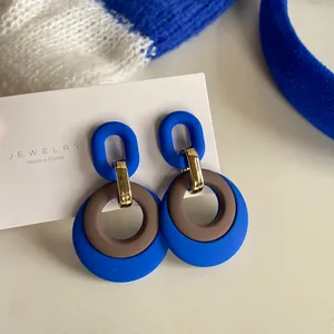 Macro view of Klein Blue retro geometric drop earrings with gold accents on a white display card