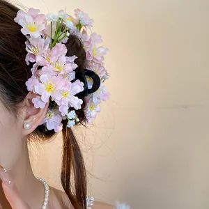Detail view of pink fabric cherry blossom hair clip worn on model's hair
