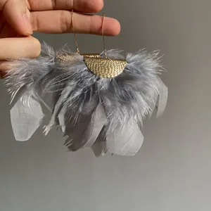 Detail view of grey feather tassel earrings with gold hammered metal accents.