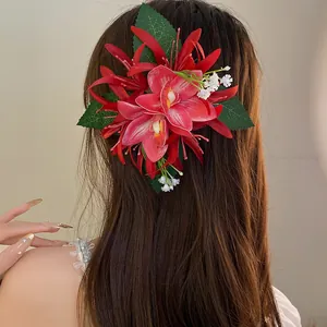 Close-up of red orchid-style fabric flower hair clip with elegant green leaf details