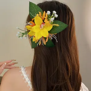 Detailed view of a large yellow fabric flower hair clip worn on long wavy brown hair