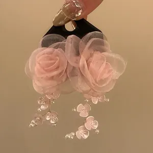 Detailed view of pink fabric rose earrings with dangling petals and pearls