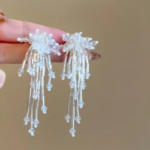 Macro detail view of elegant white beaded flower tassel earrings with shimmering crystals