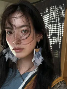 Detailed shot of elegant grey feather tassel hook earrings on an Asian model