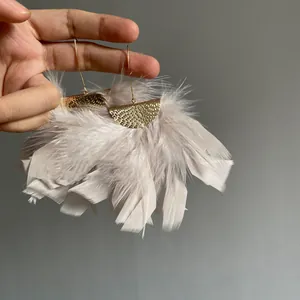 Detailed close-up showing texture of lightweight feather tassel earrings with gold hooks.