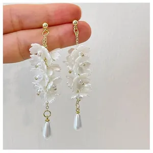 Detail view of the intricate white flower cluster earrings with a pearl teardrop pendant