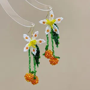 Close-up of handmade beaded flower and cherry dangle earrings