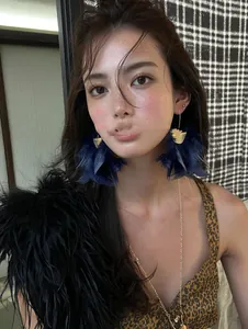 Detailed view of model wearing elegant blue feather tassel earrings with gold accents.