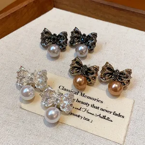 Close-up of elegant bow-knot pearl stud earrings in various metallic finishes.