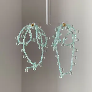 Detailed view of handmade light green beaded drop earrings with floral loop design