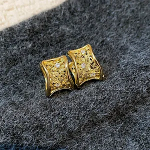 Macro di orecchini geometrici dorati con intricata filigrana e strass scintillanti