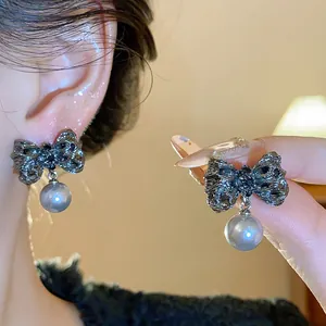 Close-up detail of dark silver textured bowknot earrings with grey pearl pendants