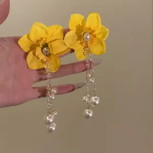 Close-up of yellow fabric flower earrings with long pearl and crystal bead tassels