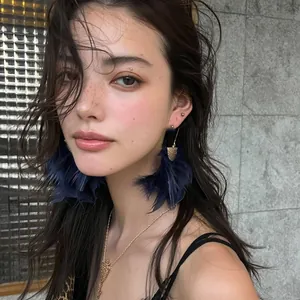 High-quality detail view of elegant navy blue feather tassel earrings worn by a fashion model
