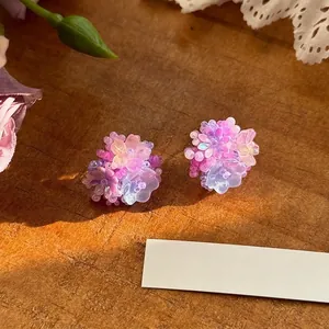 Macro shot of colorful dopamine-style floral earrings on a sunlit wooden surface