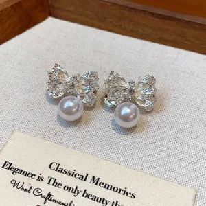 Detailed macro view of silver wrinkled bow earrings with elegant white pearl drops
