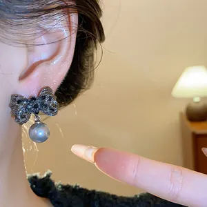 Close-up view of elegant silver needle bow pearl earring worn on the model's ear