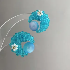 Detailed view of handmade blue beaded flower stud earrings with a tiny white floral accent