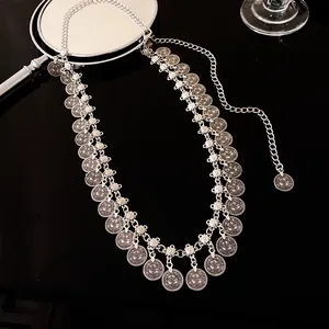 Detail van etnische zilveren muntkwastjes op een gelaagde metalen tailleketting