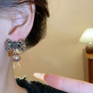 Detailed close-up of a vintage pleated metallic bowknot earring with a hanging pearl