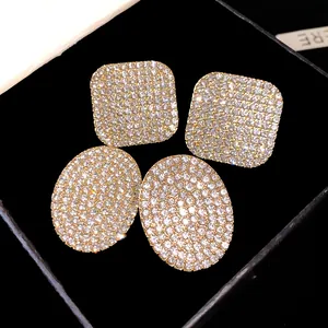 Gros plan sur des boucles d'oreilles carrées et ovales serties de strass brillants élégants