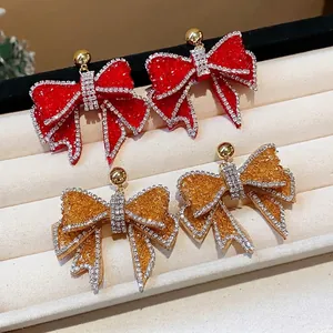 Exquisite sparkling rhinestone resin bow stud earrings displayed on a velvet jewelry tray