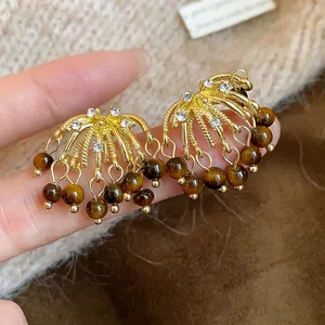 Detailed view of gold firework earrings featuring crystals and tiger eye stone beads