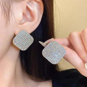 Détail macro d'élégantes boucles d'oreilles géométriques carrées avec cristaux brillants