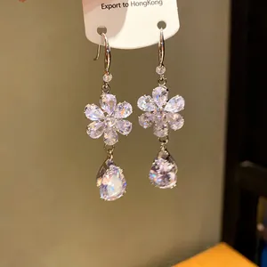 Primo piano di eleganti orecchini a fiore in zircone con pendenti a goccia su cartoncino.