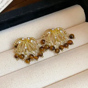 Detailed view of fireworks-style stud earrings with tiger eye tassels and crystals
