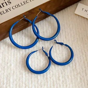 Close-up of two pairs of Klein blue hoop earrings on a white textured background.