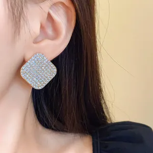 Gros plan d'élégantes boucles d'oreilles losanges en strass et argent portées par un mannequin