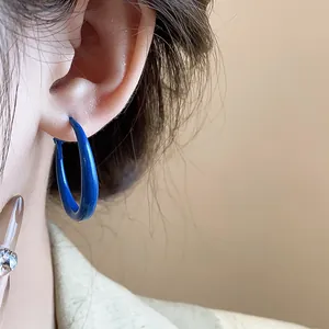 Detailed close-up showing a vibrant Klein blue exaggerated hoop earring worn on an ear