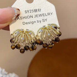 Close-up of gold fireworks earrings with tiger's eye beads and crystals