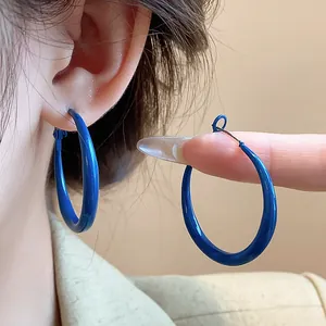 Detail shot of vibrant Klein blue hoop earrings featuring 925 silver needle posts.