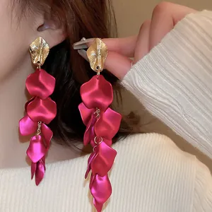 Elegant rose red petal tassel earrings with gold leaf detail shown on model's ear