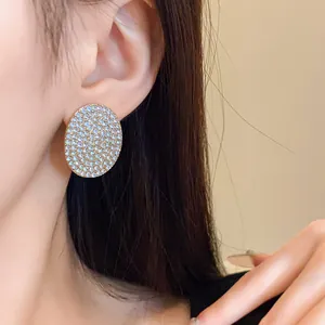 Boucles d'oreilles ovales pavées de cristaux portées pour un superbe look luxueux