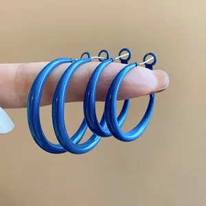 Close-up detail of Klein blue oversized hoop earrings with silver needles held on a finger.