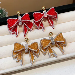 Detailed view of sparkling resin bow earrings with rhinestone edges on white tray