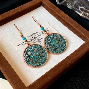 Detailed macro view of vintage bronze drop earrings with teal filigree and turquoise beads