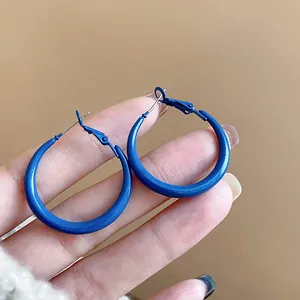 Close-up view of vintage style Klein blue hoop earrings held in hand showing scale detail