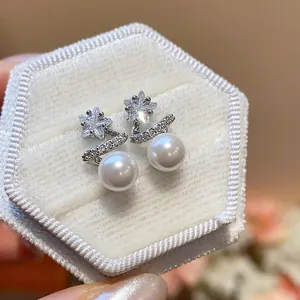 Detailed view of elegant star-shaped zircon and pearl stud earrings in a white box