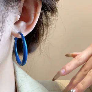 Close-up detail of bold Klein blue hoop earrings with a retro silver needle design