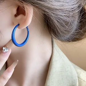 Close-up of vibrant Klein blue hoop earring worn by a model in a retro style