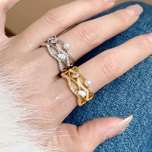 Close-up view of gold and silver plated wavy rings with pearls and zircons on a hand