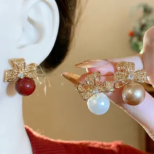 Eleganti orecchini a fiocco dorato con perle e accenti in zircone