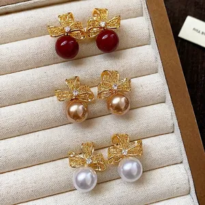 Eleganti orecchini a perno con fiocco in oro e perle in rosso champagne e bianco
