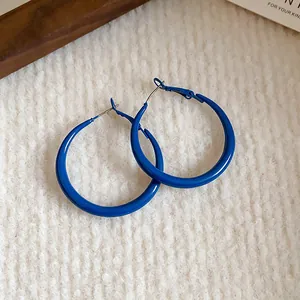 Detailed macro view of vibrant Klein blue oversized hoop earrings on soft white texture