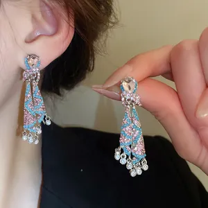 Close-up detail of vintage silver needle earrings with pink and turquoise rhinestones.