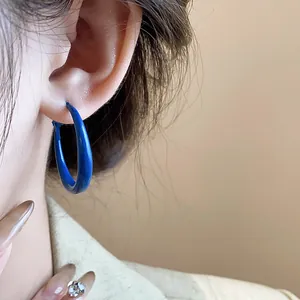 Close-up detail showing the vibrant Klein blue hoop earring worn on the ear for a stylish look